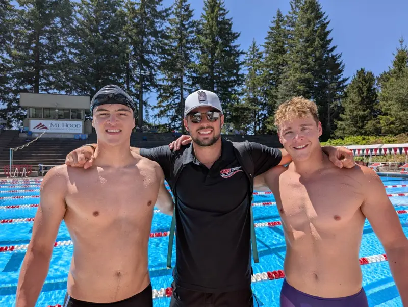 Coach Dolbinin on deck with two of his competitive swimmers at an outdoor long-course pool